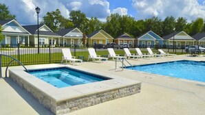 A swimming pool area with lounge chairs and a hot tub, surrounded by houses. - The Cottages 2 2BR2BA Dothan Pet Friendly Gorgeous Pool, Pickle Ball court, Gym (Dothan)