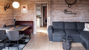 A cozy cabin interior with a dining area, a sofa, and a fireplace.
