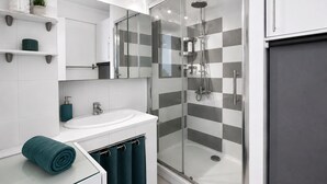 Une salle de bain moderne avec une douche à parois de verre, un lavabo blanc et un miroir au-dessus.