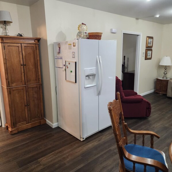 A kitchen with a white refrigerator, wooden cabinets, and a red chair.