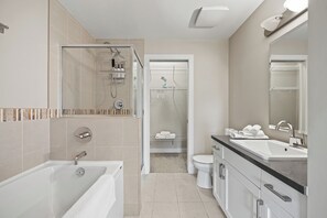 A modern bathroom with a bathtub, shower, and toilet.