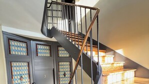 Een houten trap met een metalen leuning die naar een verdieping leidt.