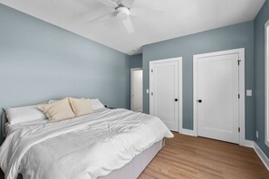 Un dormitorio con una cama, dos puertas y un ventilador de techo.