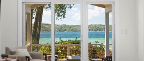 Una habitación con un amplio ventanal corredero que da a un balcón con vistas a un lago.