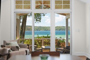 Ein Zimmer mit einer großen Schiebeglastür, die auf einen Balkon mit Seeblick führt.