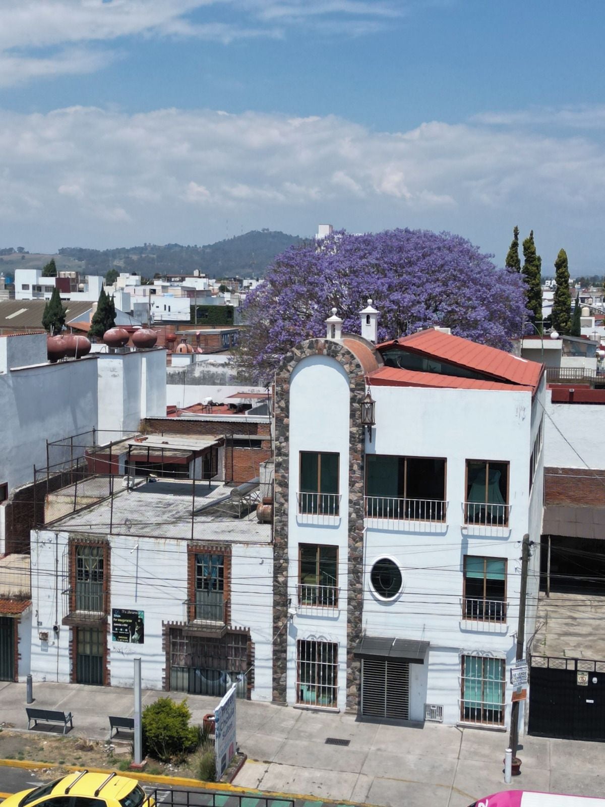 Un edificio de varios pisos con techo rojo y paredes blancas, que presenta una ventana central arqueada y una ventana circular en el segundo piso.