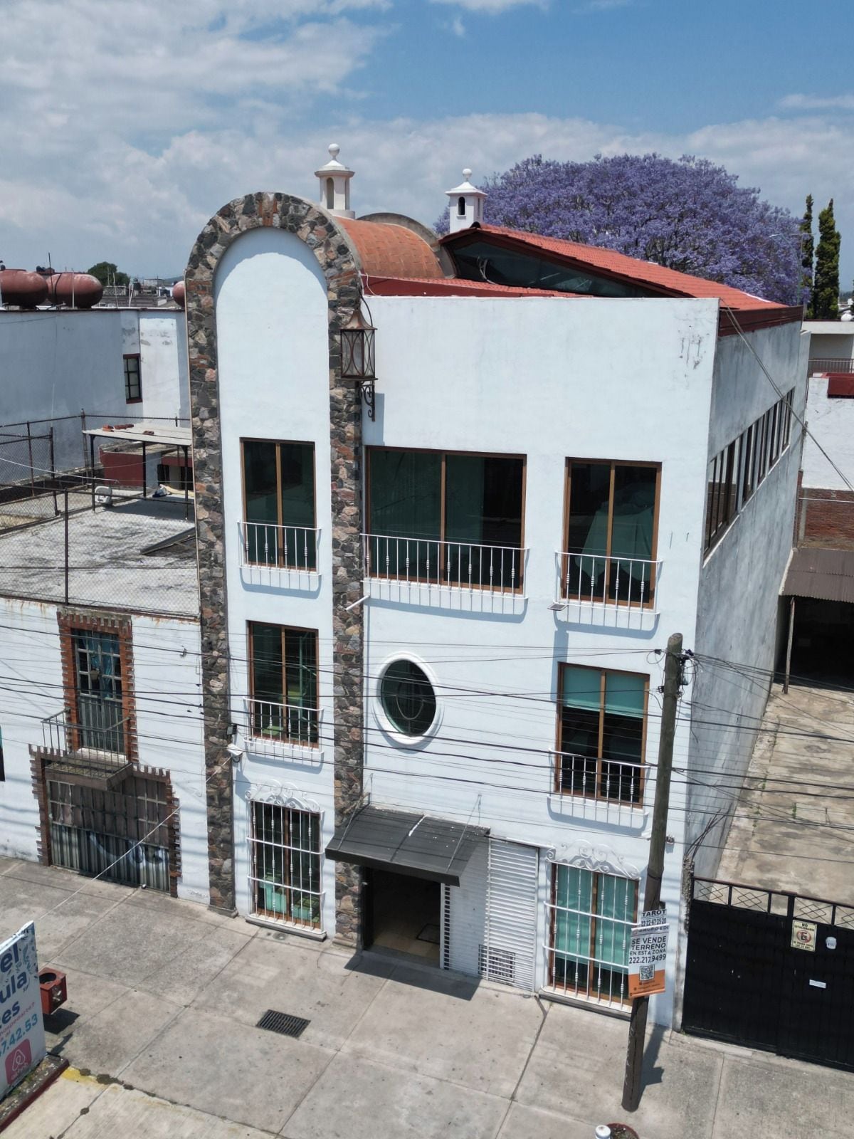 Un edificio de varios pisos con fachada de piedra, varios balcones y techo rojo.