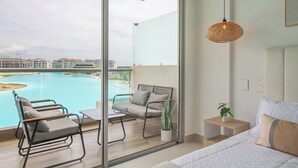 Een moderne hotelkamer met een ruim balkon, uitzicht op een zwembad en een hanglamp.