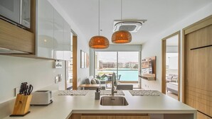 Een moderne keuken met een centraal eiland, een eethoek met uitzicht op een zwembad en houten kastjes.