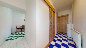 A hallway with a checkered floor, a wooden door, and a radiator. - nice apartman (Bratislava)