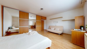 A bedroom with a large bed, a sofa, a desk, and a wardrobe. - nice apartman (Bratislava)