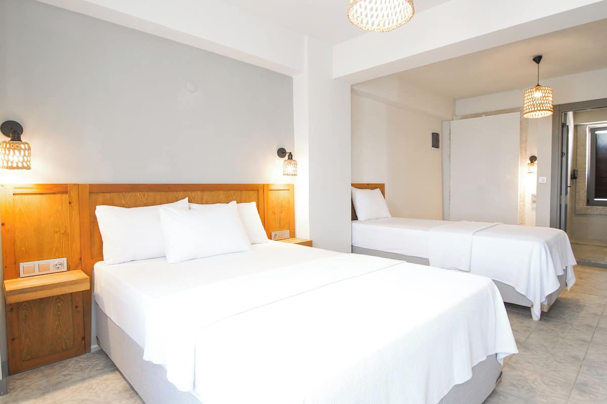 Una habitación de hotel con dos camas, cabeceros de madera, lámparas de noche y un espejo grande.