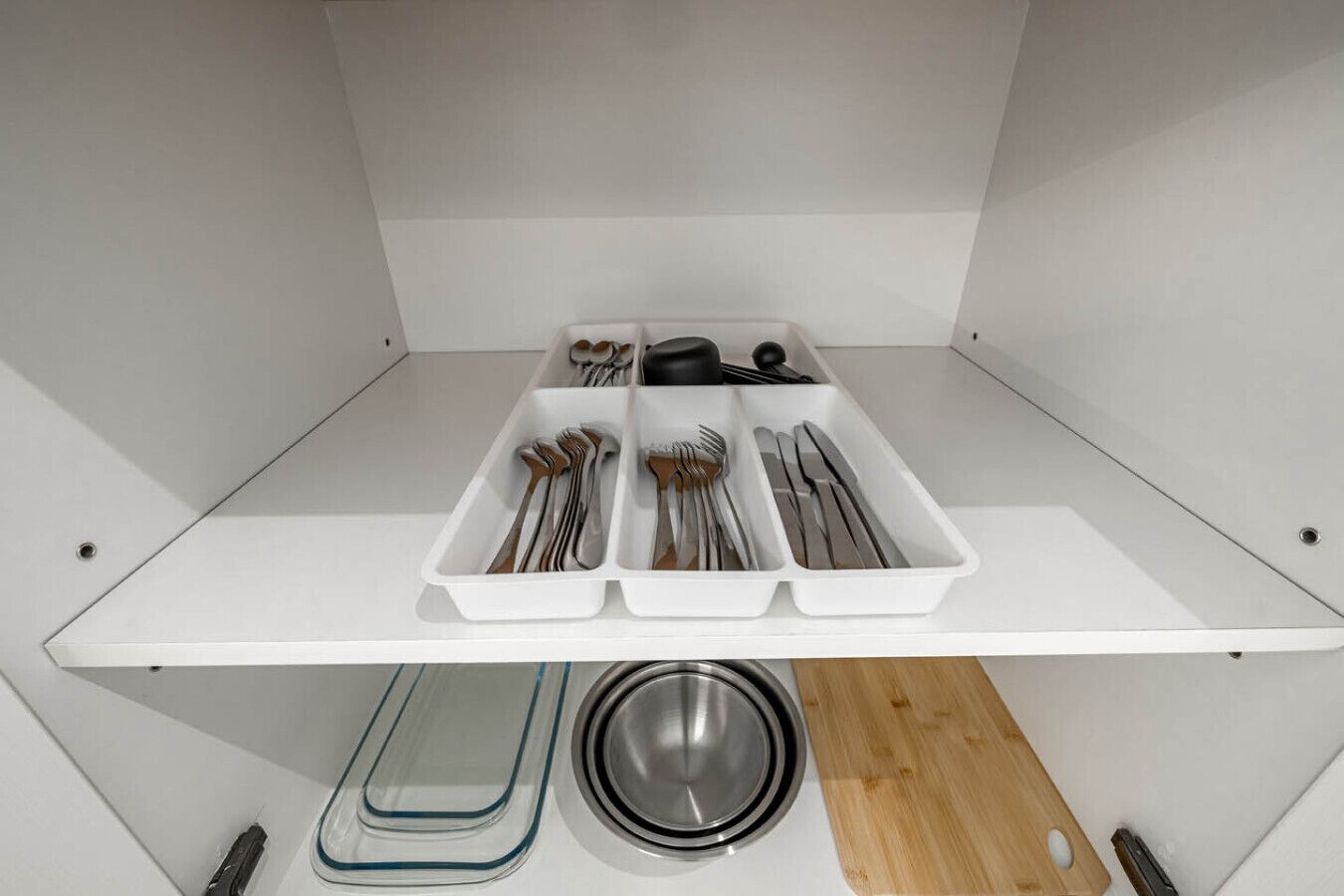 A kitchen with white cabinets, a white countertop, and a stainless steel sink.