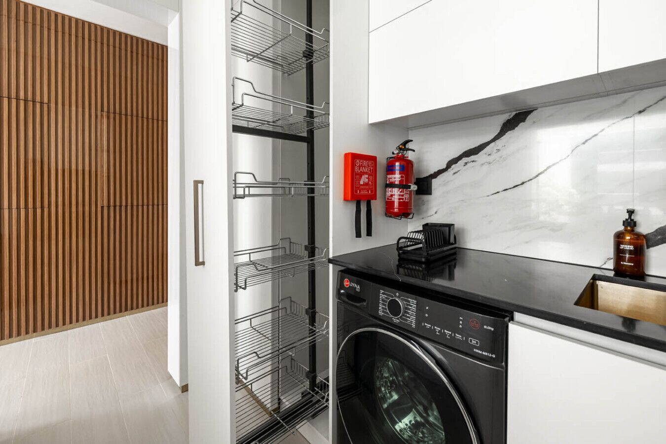 A modern kitchen with a built-in washing machine, a wooden panel wall, and a marble backsplash.