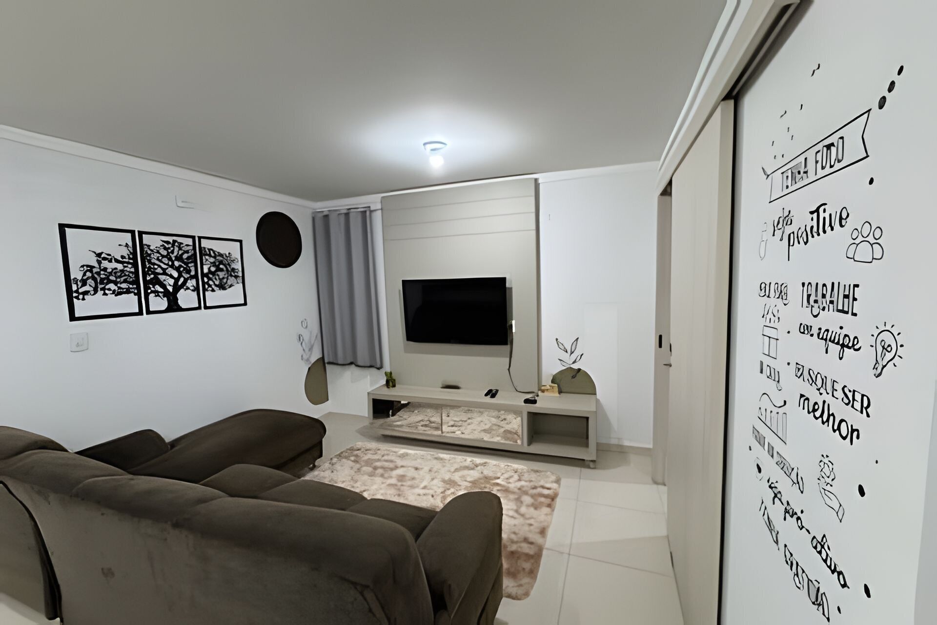 A living room with a sofa, TV, and wall art.