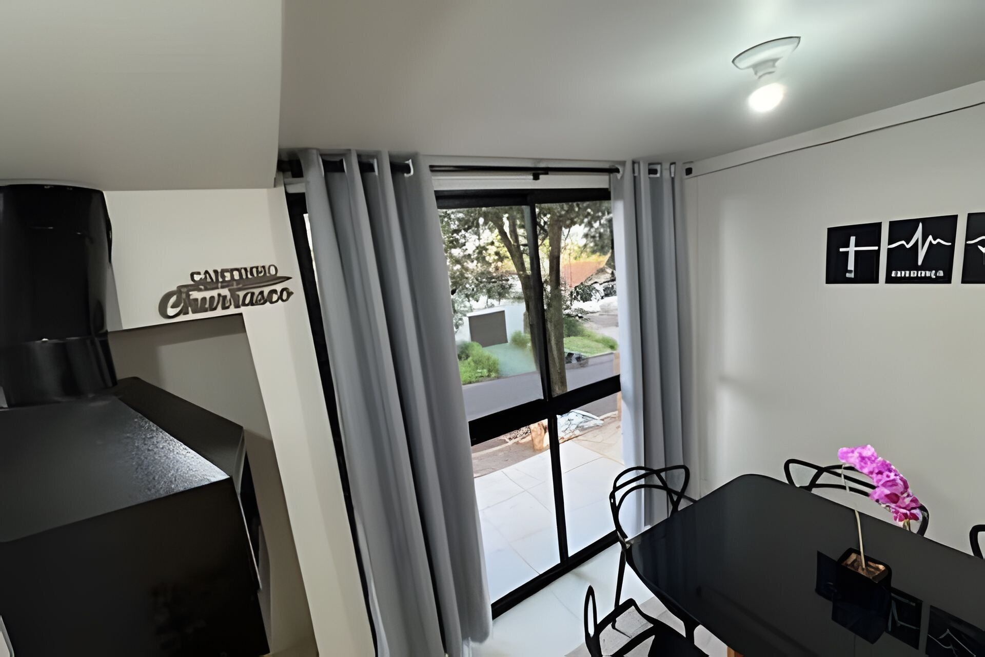 Una habitación moderna con zona de comedor, un ventanal con cortinas y un cartel en la pared.