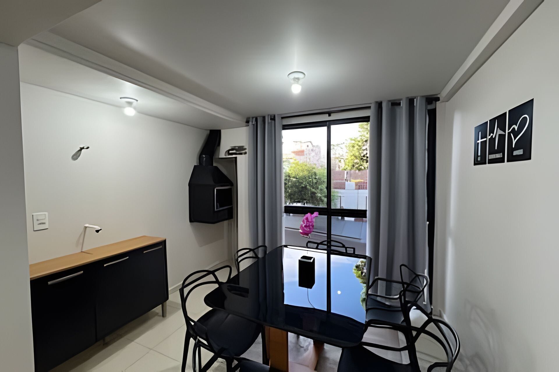 Un comedor compacto con una mesa y sillas, un horno empotrado, una ventana con cortinas y vistas al exterior.