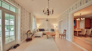 A spacious living room with a large sofa, a round coffee table, and a dining area with wooden furniture.