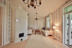 Ein großzügiger Wohnraum mit Kamin, zwei Sofas, einem Couchtisch und einer Kristallleuchtre.