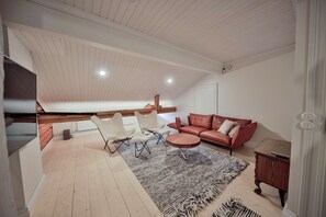 Un loft espacioso con techo alto, una zona de estar acogedora con un sofá de cuero y sillas blancas, una mesa de comedor de madera y una alfombra grande.