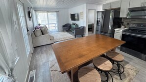Een moderne keuken met roestvrijstalen apparatuur, een houten eettafel met krukken en een gezellige zithoek met een bank en fauteuils.
