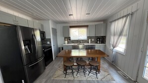 Een moderne keuken met een centraal eiland, barkrukken en een roestvrijstalen koelkast.