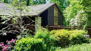 A rustic cabin with a stone foundation, wooden exterior, and a wooden deck.