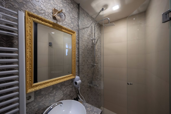 A bathroom with a large mirror, a hairdryer, and a shower.