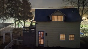 Ett envåningshus med ett mörkt tak, en ytterdörr och en liten veranda.