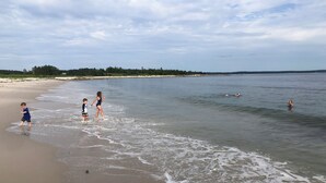 Une plage où l’on voit des gens se promener et nager dans l’eau.