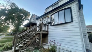 A two-story house with a wooden staircase leading to a porch. - Lower level luxury (Chicago)