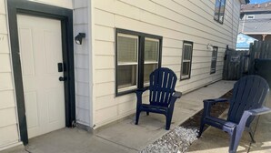A house with a white exterior, a black door, and two blue Adirondack chairs on the porch. - Lower level luxury (Chicago)