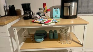 A kitchen counter with a coffee maker, a toaster, and a blender. There are also green plates, a jar of jam, and a bottle of milk on the counter. - Lower level luxury (Chicago)