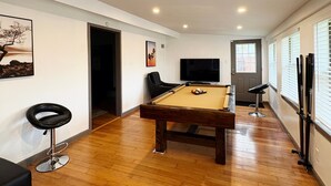 A room with a pool table, a TV, and a bar area.