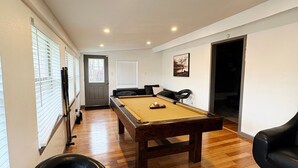 A spacious room with a pool table, a pool cue rack, and a pool table chair.