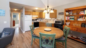Una cocina con armarios de madera, estufa, refrigerador, microondas y una mesa de comedor con sillas.