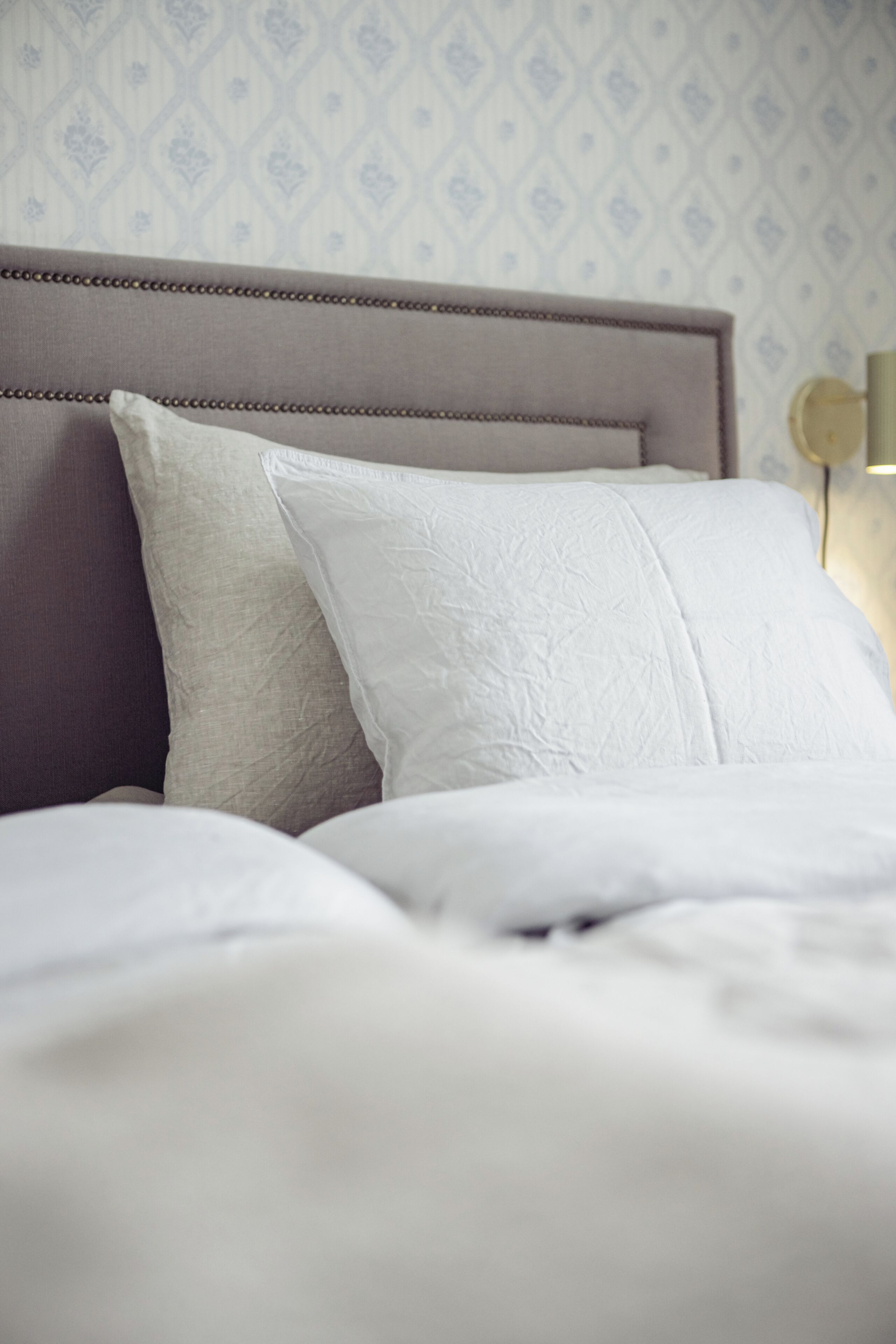 A neatly made bed with a headboard and pillows.