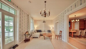 A spacious living room with a large sofa, a round coffee table, and a dining area with wooden furniture. - In the eastern wing, 6 people accommodate in a three two-person rooms (Unknown)