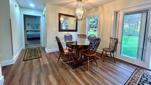 A dining area with a round table and chairs, a chandelier, and a large mirror on the wall.