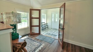 A room with hardwood flooring, a wooden bench, a patterned rug, and a door leading to another room.