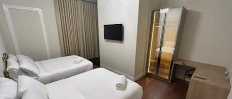 Une chambre d’hôtel avec deux lits, une télévision, un miroir et un bureau.