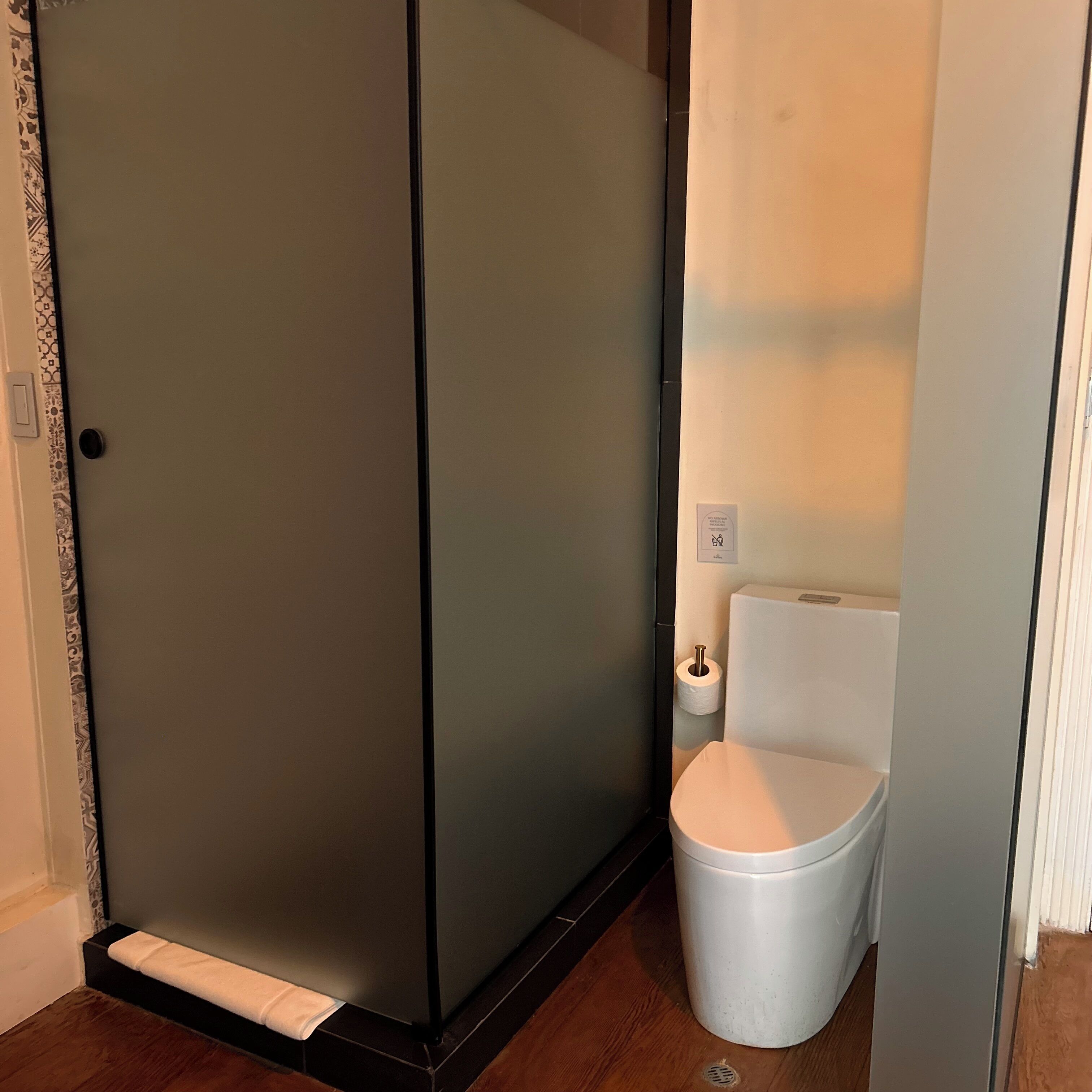 Un baño con inodoro, un cesto de basura y cabina de ducha.