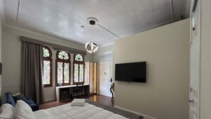 A bedroom with a large bed, a desk, a TV, and a window with curtains. - Andara Hotel (Lima)