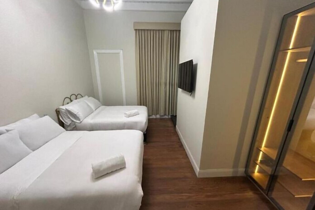 A hotel room with two beds, a television, and a sliding door.