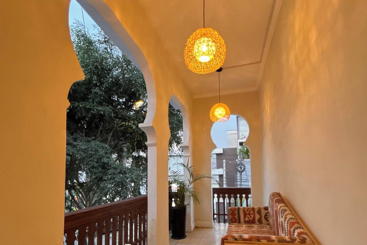 A corridor with arches, a bench, and hanging lights.