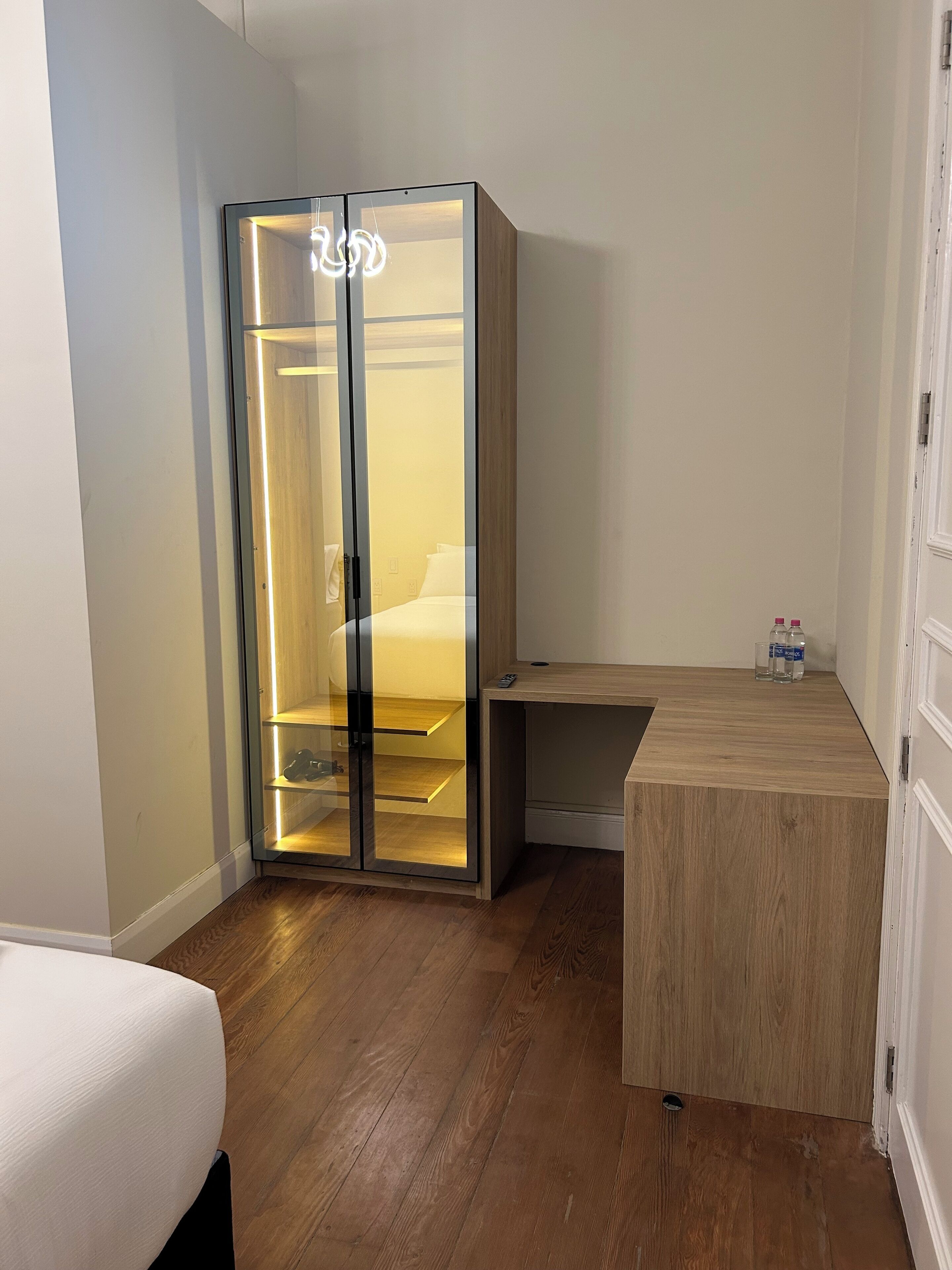 Una habitación moderna con un armario de madera, una mesita de noche y una cama.