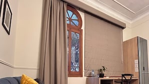 A room with a grey sofa, a wooden desk, a chair, and a wardrobe. - Andara Hotel (Lima)