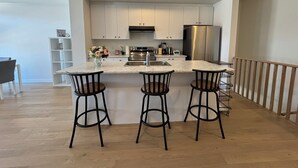 Uma cozinha moderna com uma ilha central, eletrodomésticos de aço inoxidável e banquetas.