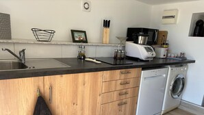 Una cocina moderna con una isla de madera, lavavajillas integrado y una encimera negra.