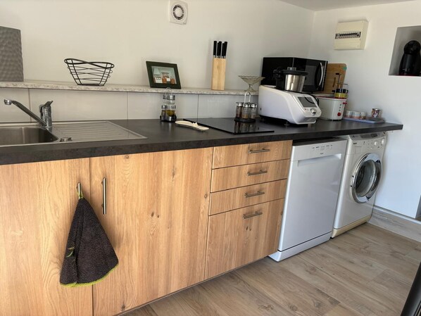 Una cocina moderna con una isla de madera, lavavajillas integrado y una encimera negra.
